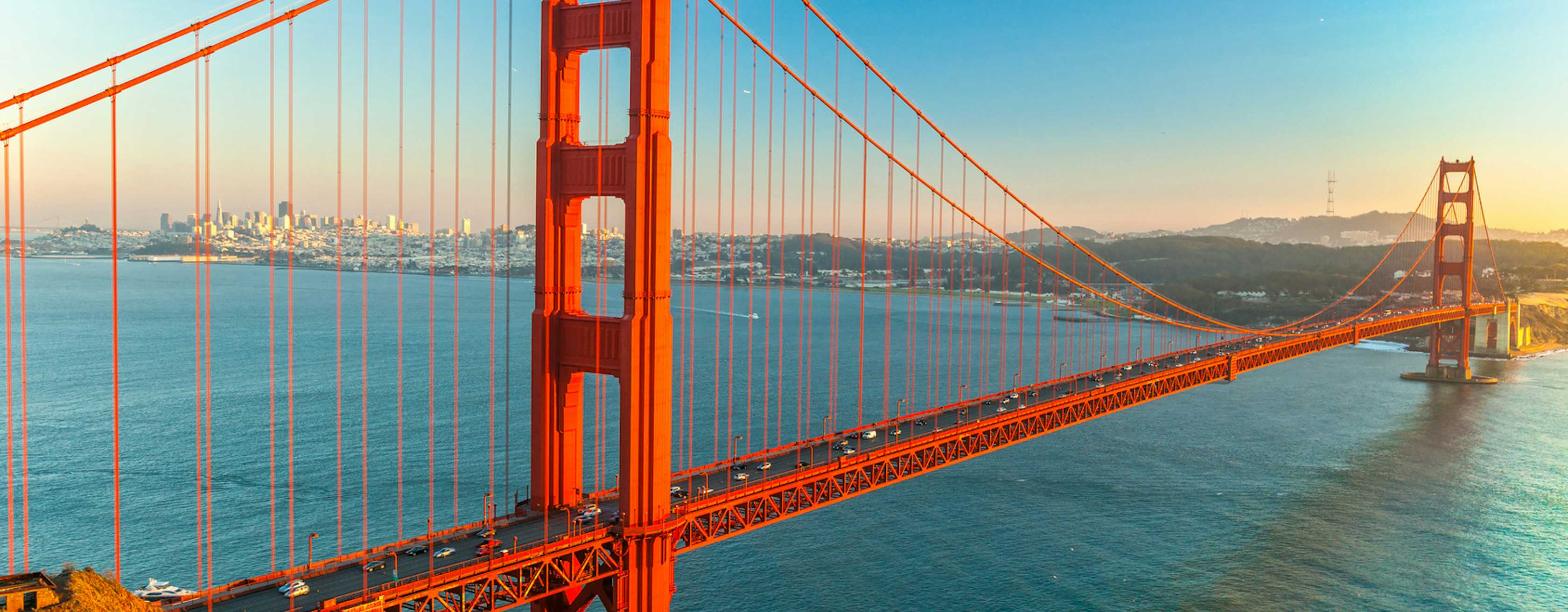 The Golden Gate Bridge at golden hour, with San Francisco visible across the bay